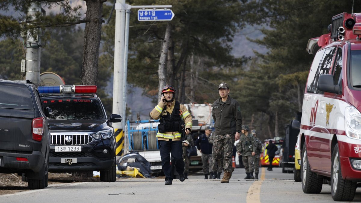El personal de los servicios de rescate y los soldados caminan cerca del lugar del bombardeo accidental de un avión de combate, en Pocheon, el 6 de marzo de 2025.