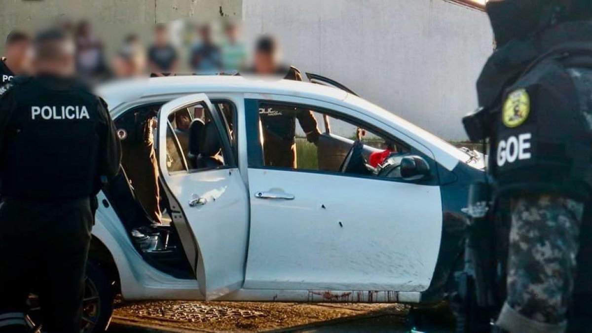 Agentes policiales custodian un vehículo involucrado en la masacre ocurrida en Socio Vivienda 2, la tarde del jueves 6 de marzo.