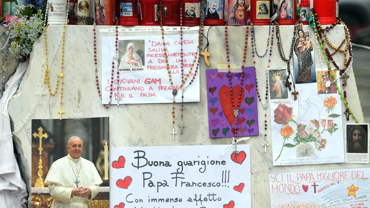 Velas, rosarios y mensajes de apoyo al papa Francisco se exhiben en la estatua del papa Juan Pablo II junto al Hospital Universitario Gemelli.
