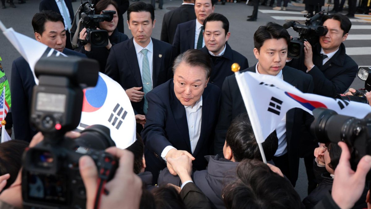 El presidente destituido, Yoon Suk Yeol, estrecha la mano de un partidario al llegar frente a su residencia oficial después de ser liberado de su detención, el 8 de marzo de 2025.