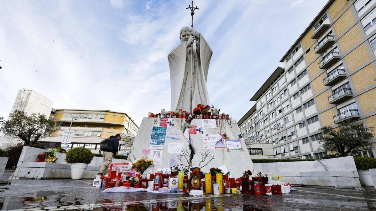 Un feligrés católico reza junto a la estatua de Juan Pablo II, frente al hospital Gemelli de Roma.