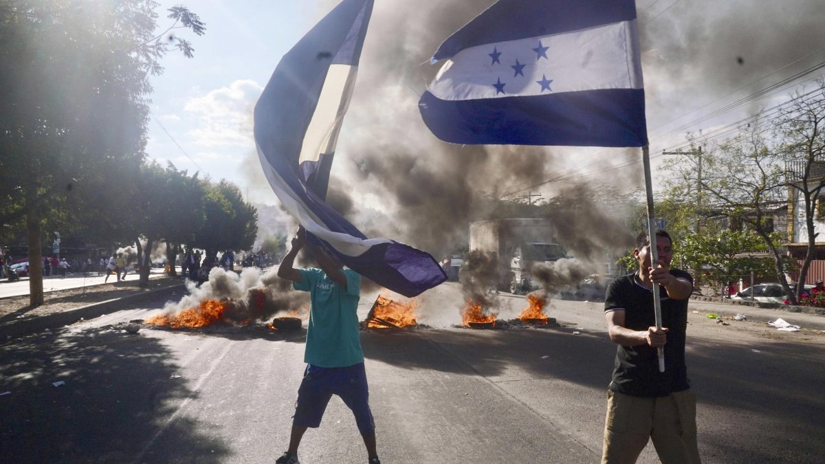 Simpatizantes del Partido Nacional de Honduras ondean banderas y queman llantas en una calle exigiendo que lleguen urnas de votación a su barrio, este domingo en Tegucigalpa (Honduras).