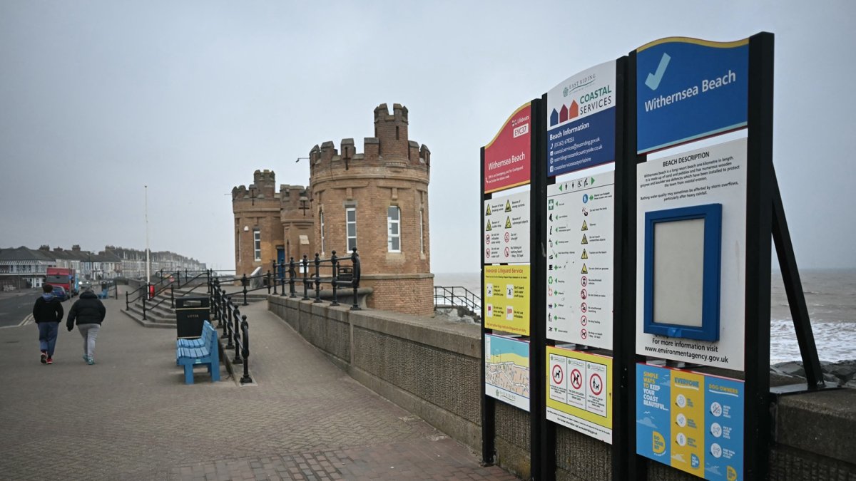 Los peatones caminan junto a las torretas de la entrada del antiguo muelle de Withernsea, en la costa este de Inglaterra, el 10 de marzo de 2025.