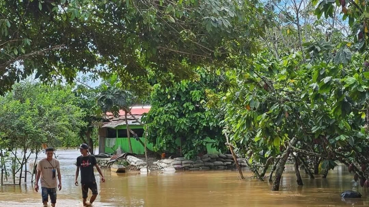 Inundación. Dos jóvenes caminan en un área anegada de Los Ríos.