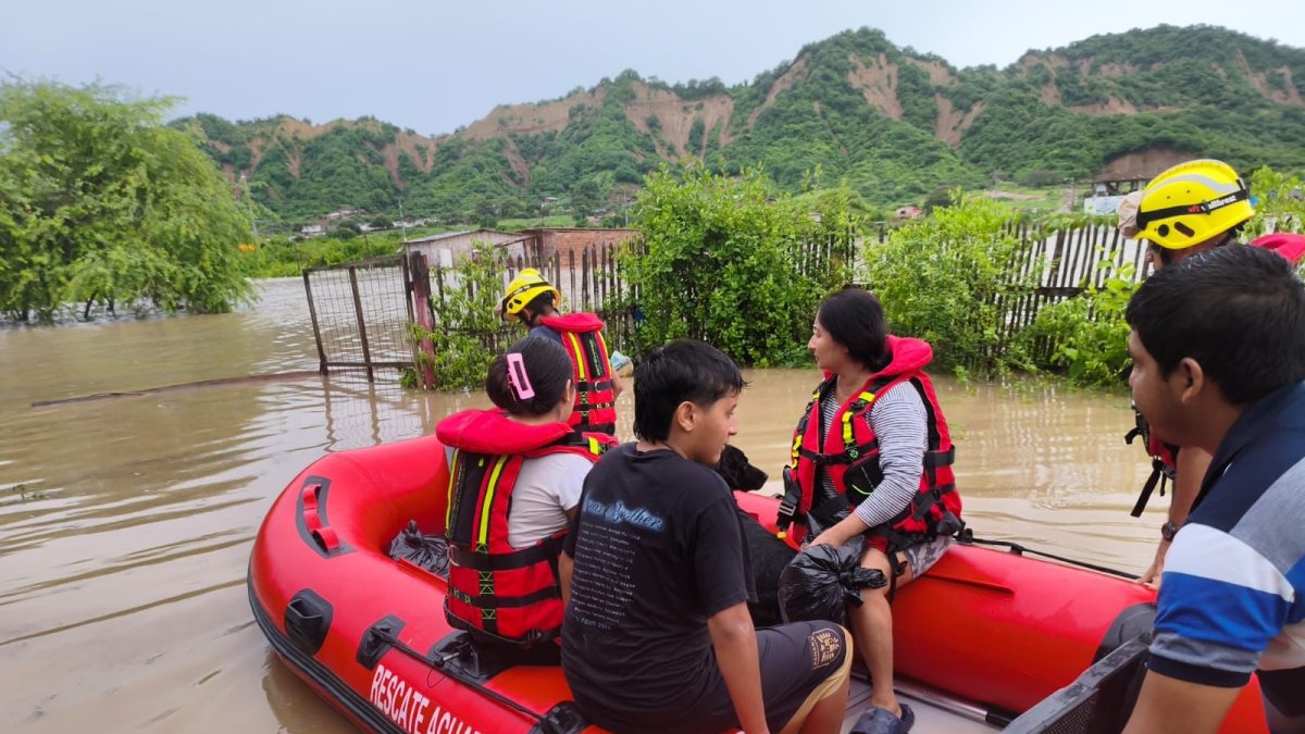 Inundaciones en San Clemente debido al temporal invernal en Manabí, con familias evacuadas por bomberos en lanchas.