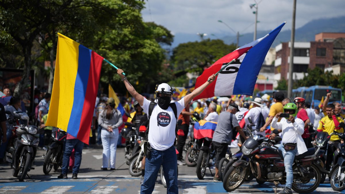 Un hombre sostiene banderas durante una manifestación este martes, en Cali. Sindicalistas, empleados oficiales y simpatizantes del Gobierno salen a las calles.