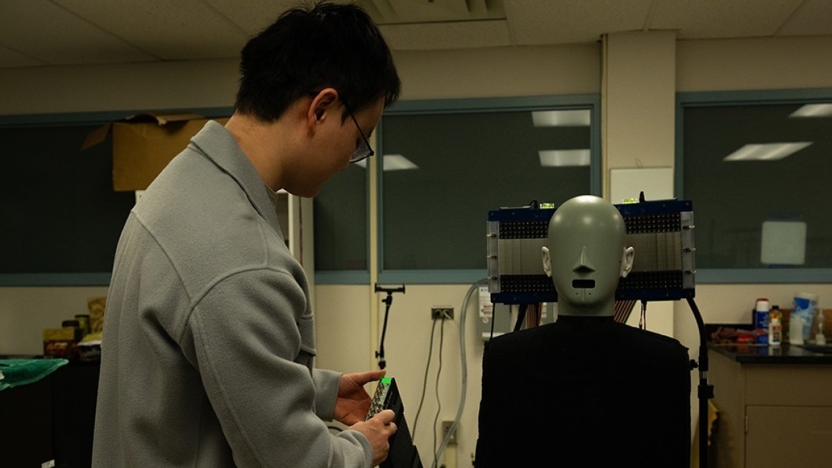 Uno de los investigadores Jia-Xin Zhong, usa un ma niquí con micrófonos en las orejas para medir la presencia o ausencia de sonido a lo largo de una trayectoria ultrasónica.