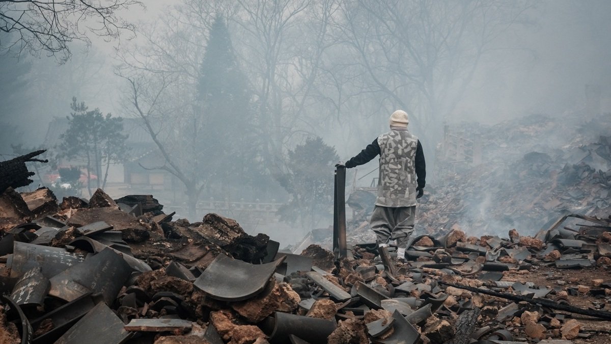 Un auxiliar caminando sobre los escombros causados tras la expansión de los incendios forestales surcoreanos.