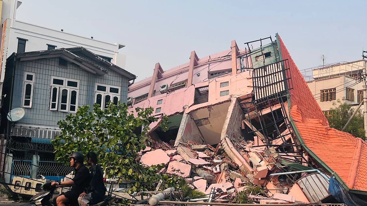 Gente circula al frente de un edificio colapsado tras un terremoto ocurrido en Birmania el 28 de marzo de 2025.