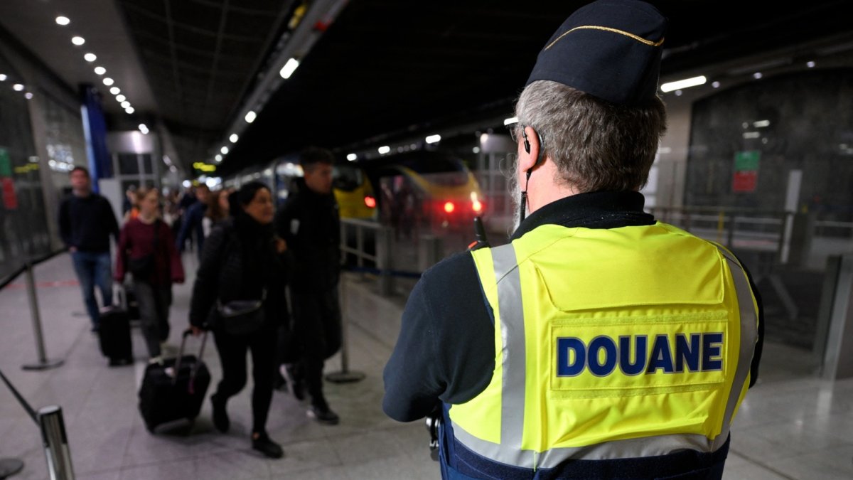 Un agente de aduanas francés vigila los viajeros de un aeropuerto.