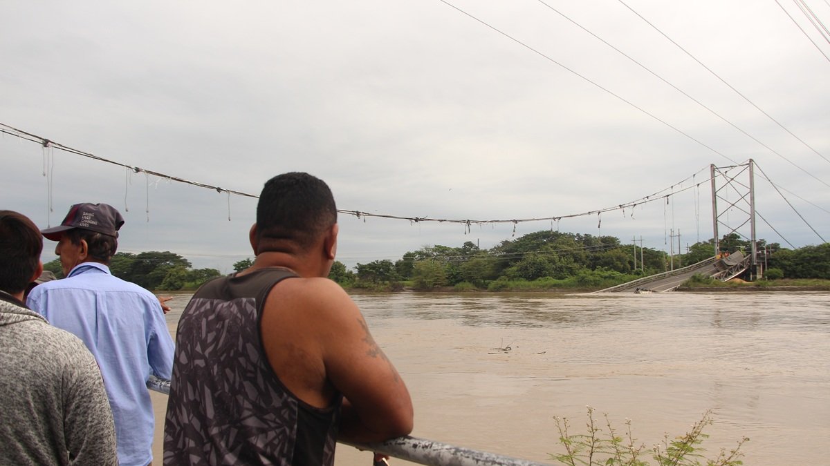 Pobladores de la parroquia Magro observan con asombro el puente Gonzalo Icaza Cornejo, colapsado y sumergido en las aguas del río Daule.