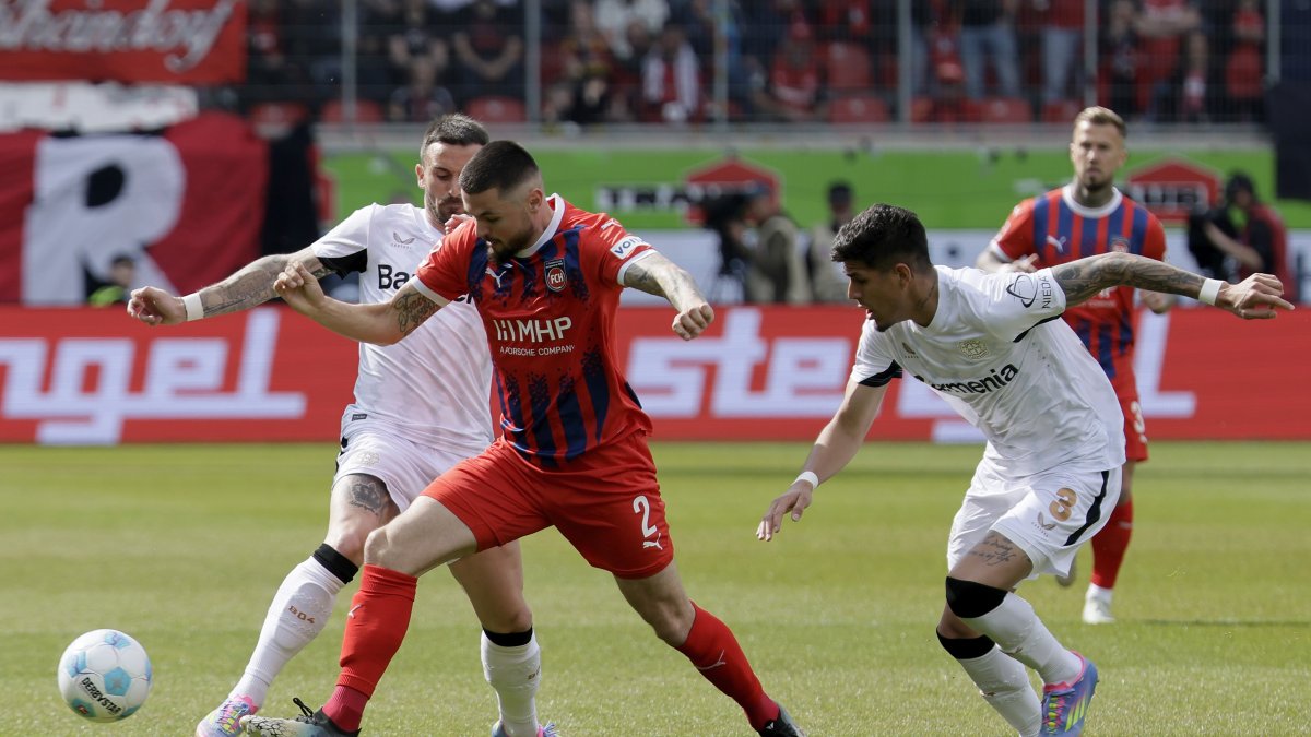 Marnon Busch de Heidenheim (C) reacciona ante el acoso de Aleix Garcia (i) y el ecuatoriano Piero Hincapie del Leverkusen (R) durante el cotejo de Bundesiga.