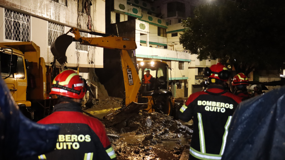 Los bomberos y maquinaria pesada trabajan para retirar los escombros tras el deslizamiento en Guápulo, que afectó varias viviendas.