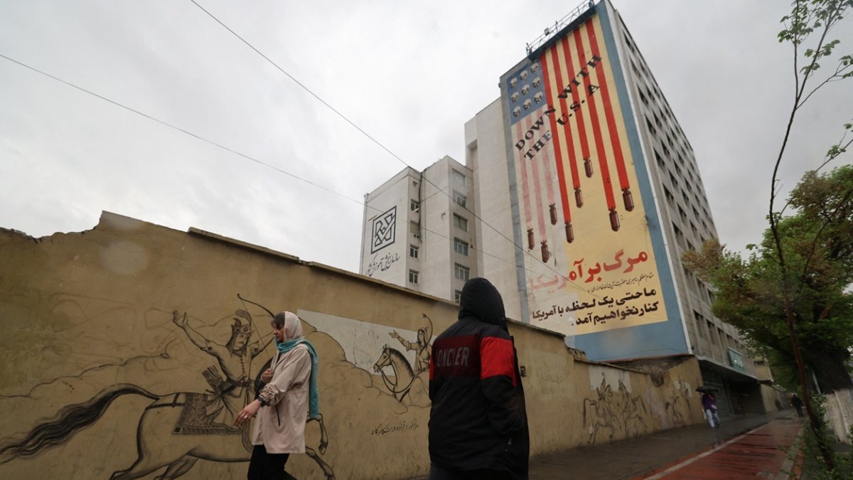 Transeúntes pasan por calles iraníes con el trasfondo de propaganda antiestadounidense
