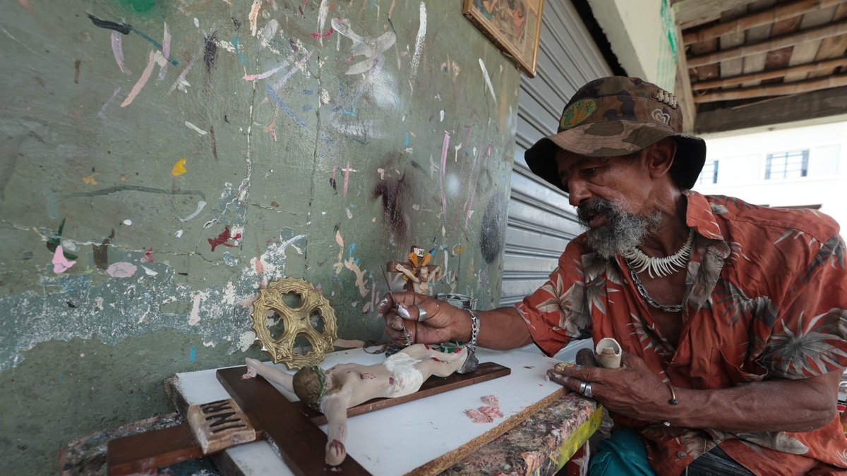 Gustavo Vera retoca la imagen de Cristo crucificado en los exteriores de un taller en General Gómez y Los Ríos. En el sitio se realiza esta actividad desde hace más de 50 años.