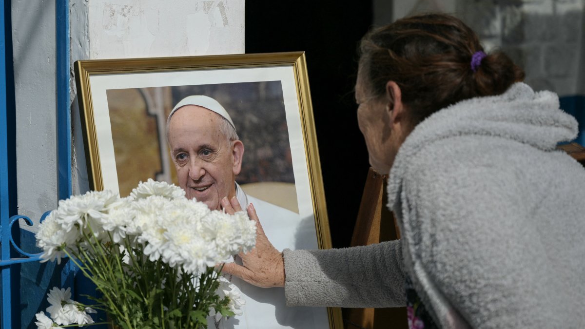 Una mujer rinde homenaje ante un retrato del difunto Papa Francisco frente a la Parroquia de Caacupé en Buenos Aires el 21 de abril de 2025.