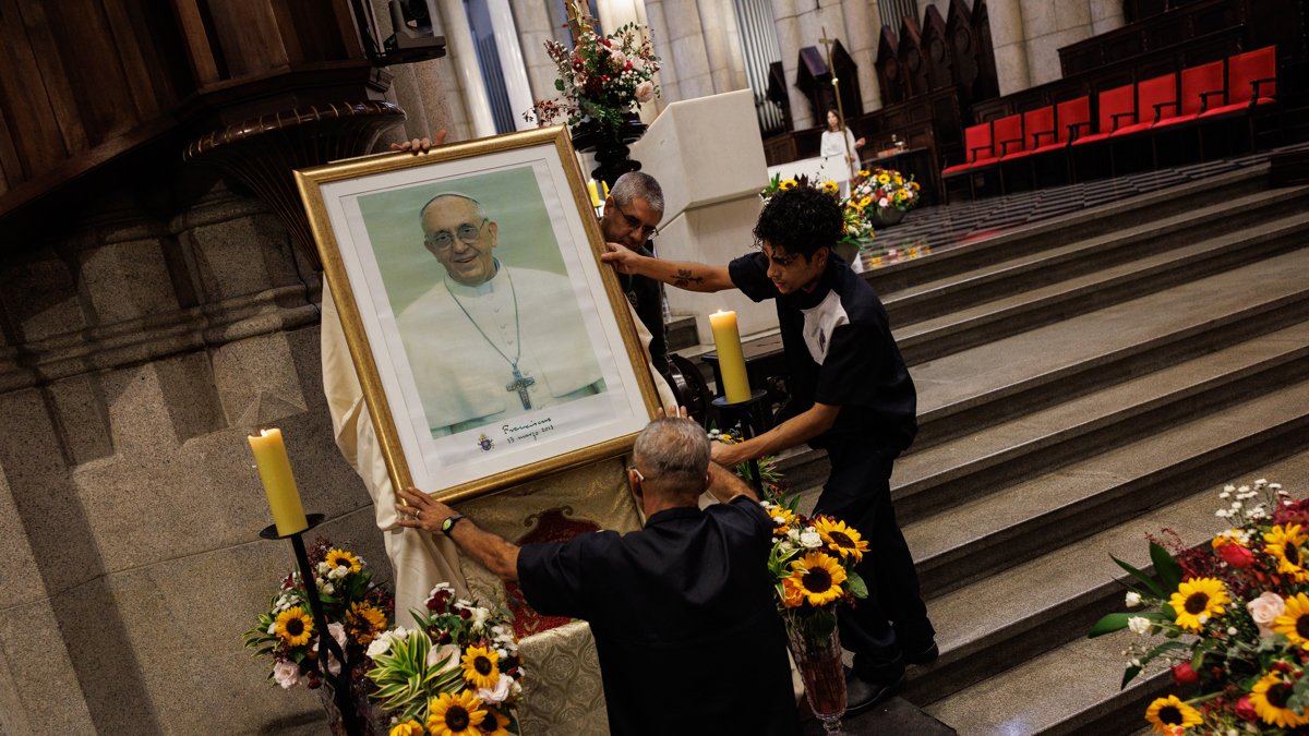 Personas acomodan un retrato del papa Francisco antes de una misa misa en honor este lunes, en la Catedral Metropolitana de la Sé, en el centro de la ciudad de São Paulo (Brasil).