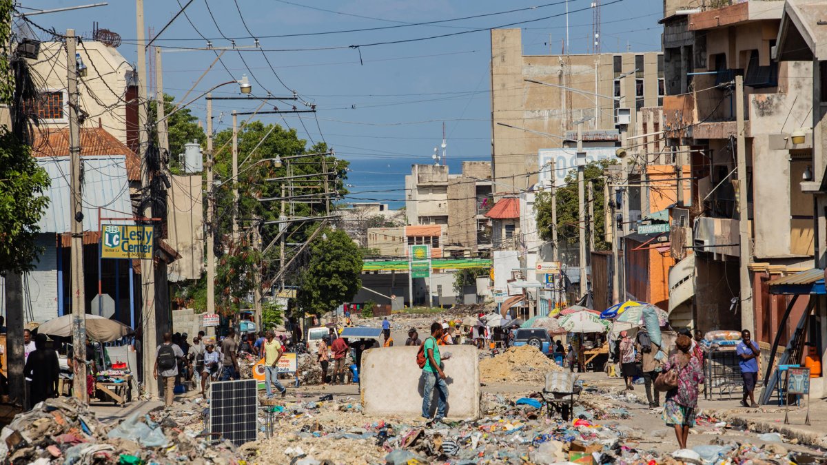 Decenas de personas al caminar por una calle en ruinas y llena de basura cerca al Palacio Nacional, en Puerto Príncipe (Haití).