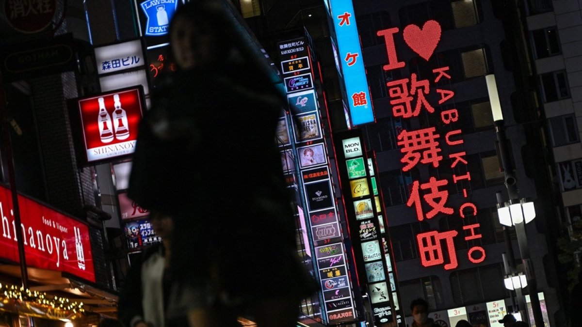 Personas caminando por una calle junto al letrero de neón 