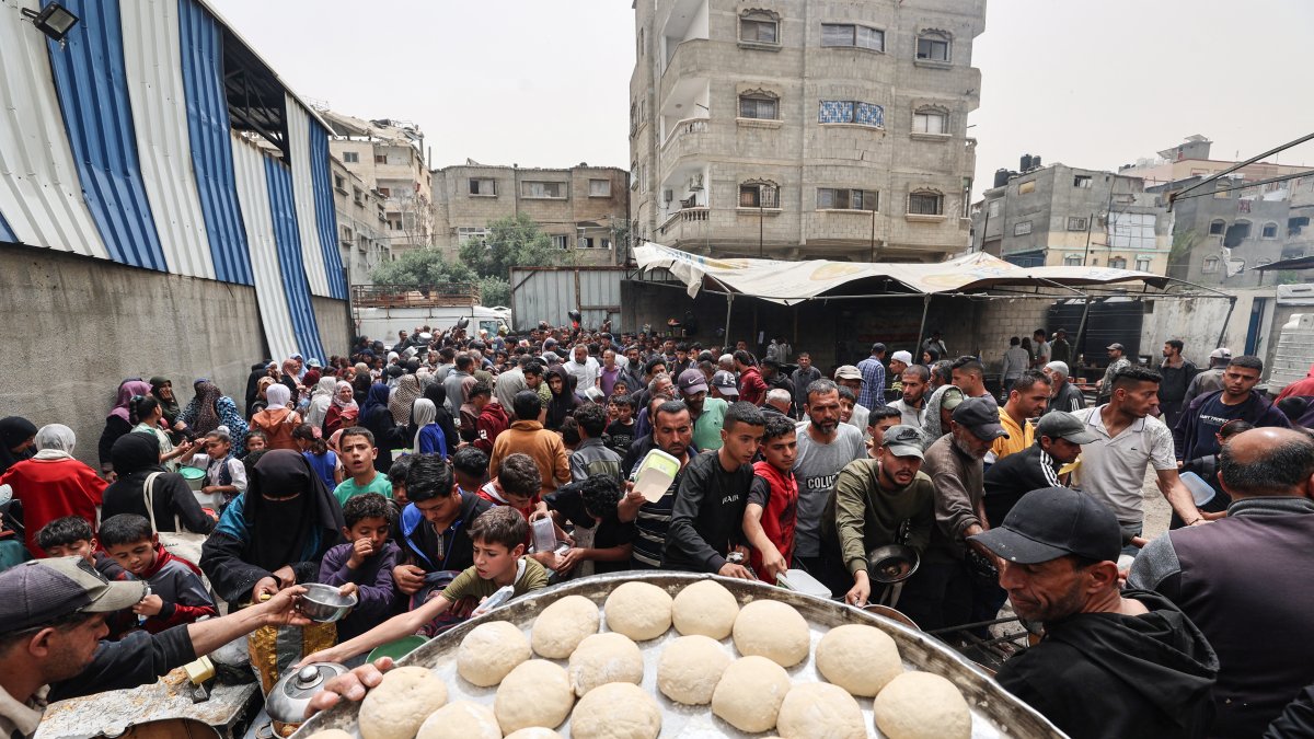 Palestinos se reúnen para recibir una comida caliente en un centro de distribución de alimentos en el campamento de refugiados de Nuseirat