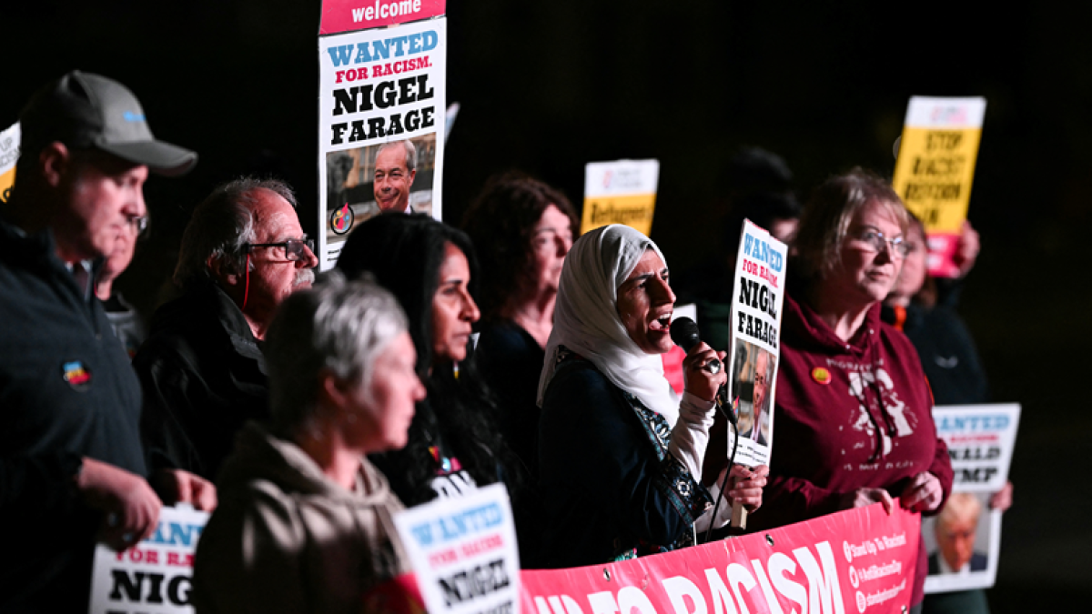 Manifestantes sostienen cartel con imagen del presidente y diputado del partido de ultraderecha británico Reform UK, Nigel Farage, que dice 