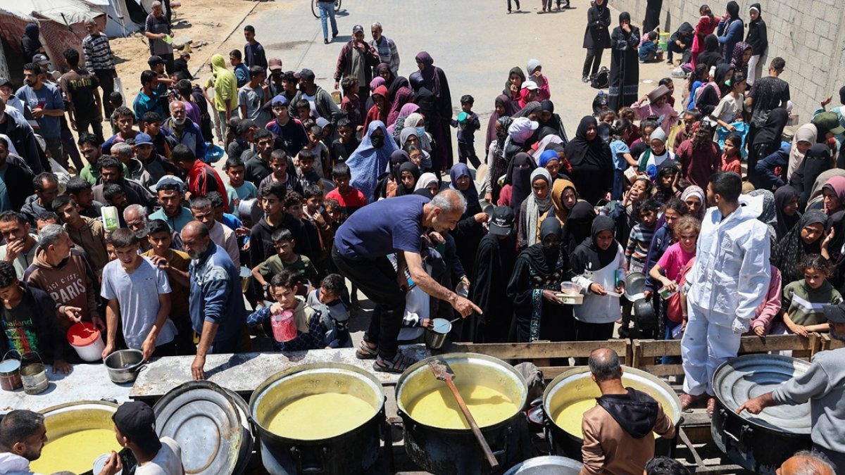 Palestinos desplazados hacen cola para recibir una porción de comida caliente en un comedor benéfico en el campo de refugiados de Nuseirat, en el centro de la Franja de Gaza, el 5 de mayo de 2025.