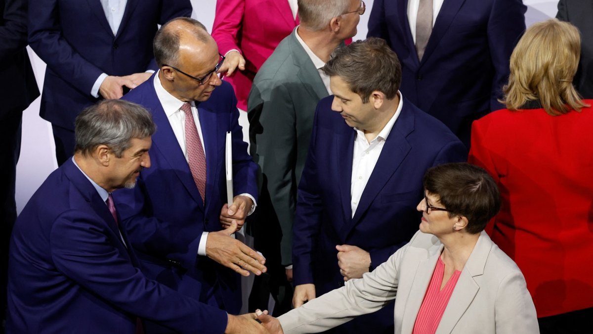 El líder de la Unión Socialcristiana (CDU), Friedrich Merz (al fondo, izq.), estrecha la mano del copresidente del SPD, Lars Klingbeil, tras firmar un acuerdo de coalición.