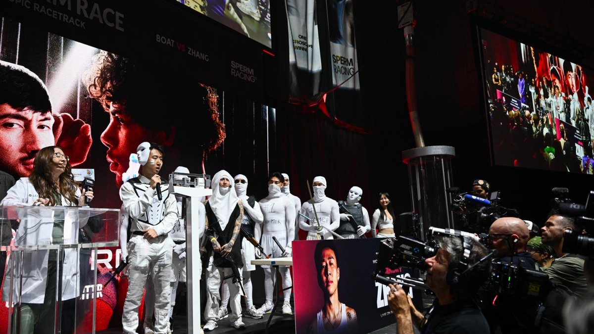 El youtuber Jimmy Zhang (derecha) está de pie en el escenario con un séquito disfrazado de esperma en el pesaje preliminar de la competencia de Sperm Racing en Los Ángeles, el 25 de abril de 2025.