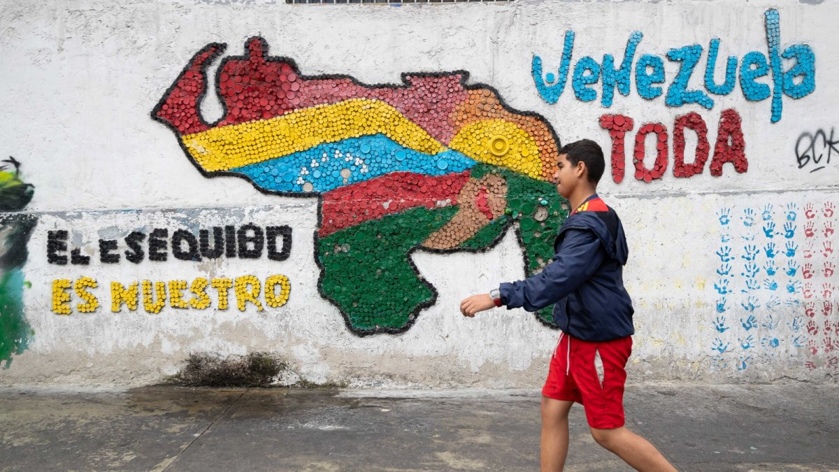 Fotografía del 2 de abril del 2025 de una persona caminando frente a un mural con el mapa de Venezuela en Caracas (Venezuela).