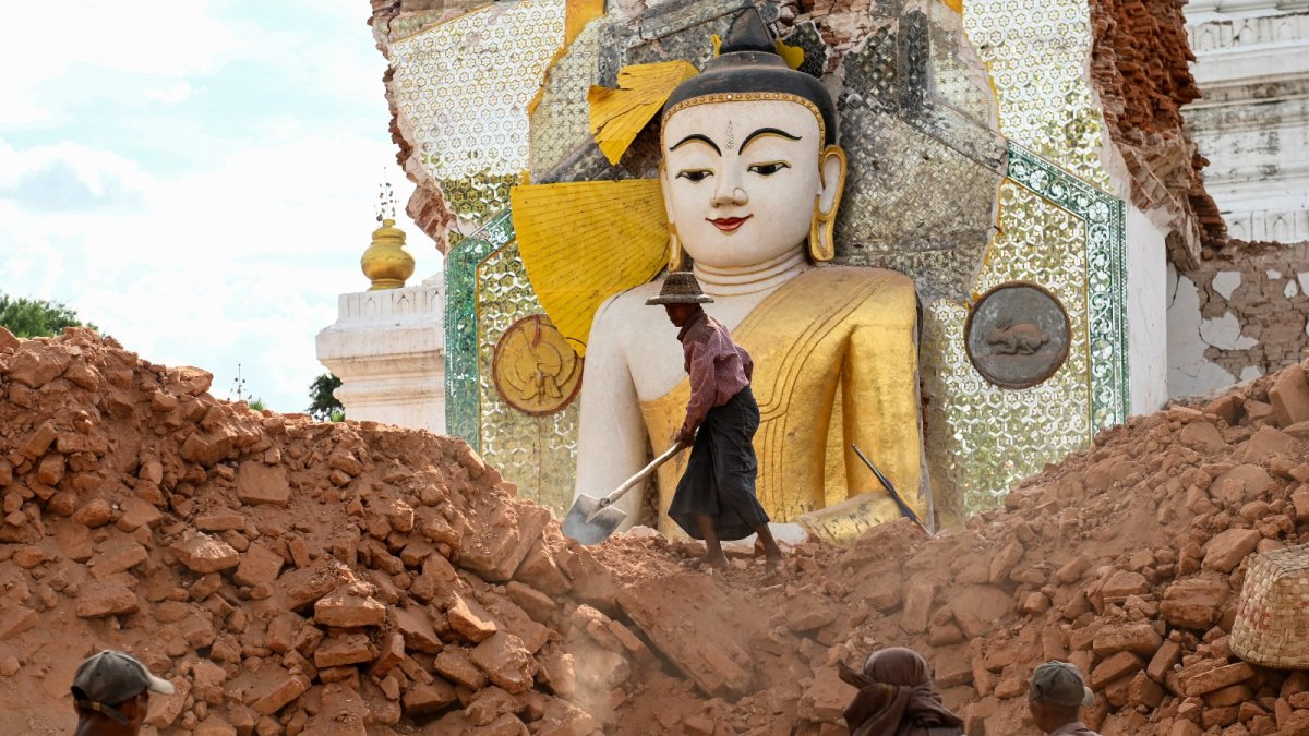 Fotografía del 12 de abril de 2025 muestra a un hombre retirando escombros alrededor de una dañada estatua de Buda, en Inwa (afueras de Mandalay)