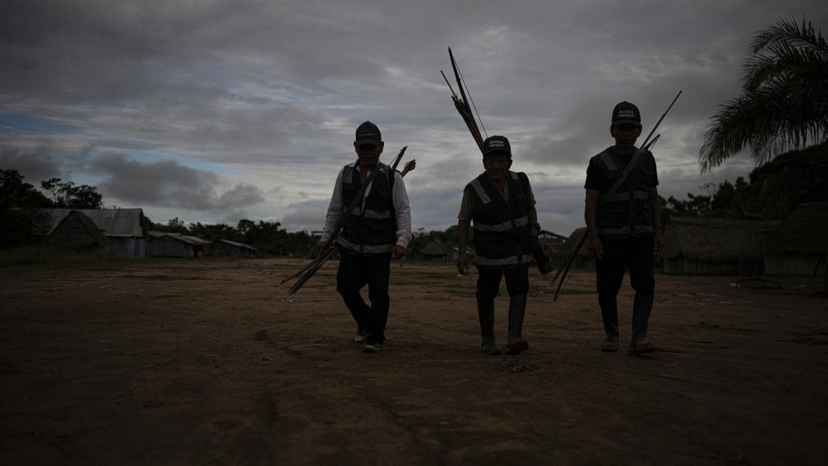 Miembros de la Guardia Indígena Shipibo Konibo caminan para participar en una reunión de coordinación antes de salir a patrullar contra los madereros ilegales en Caimito, departamento de Ucayali, Perú