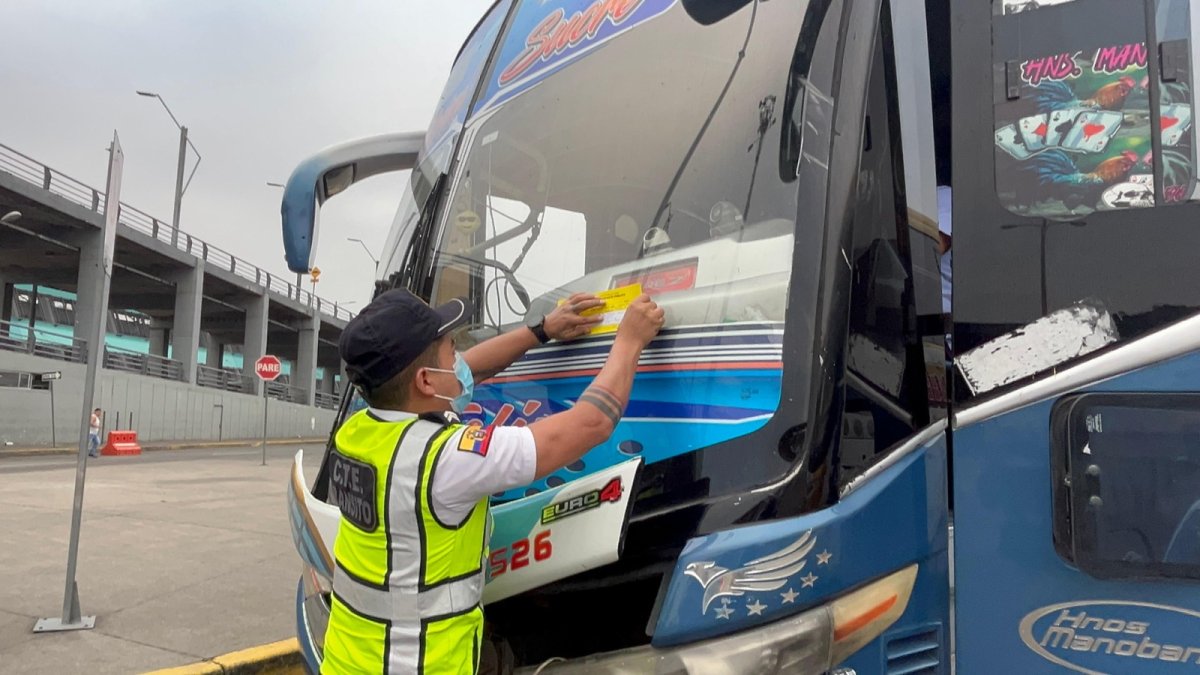 Un agente de la CTE coloca un sticker en uno de los buses sancionados, la mañana de este jueves 22 de mayo.