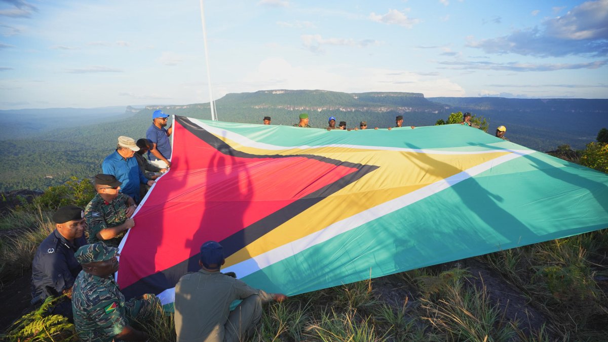 Hombres desplegando una bandera de Guyana en la montaña Pakrampa, en la aldea de Arau, región Esequibo (Guyana).