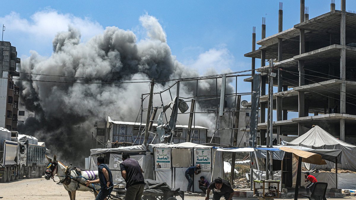 Palestinos intentan refugiarse mientras se eleva el humo tras un ataque aéreo israelí al oeste de la ciudad de Gaza, en la Franja de Gaza, el 23 de mayo de 2025.