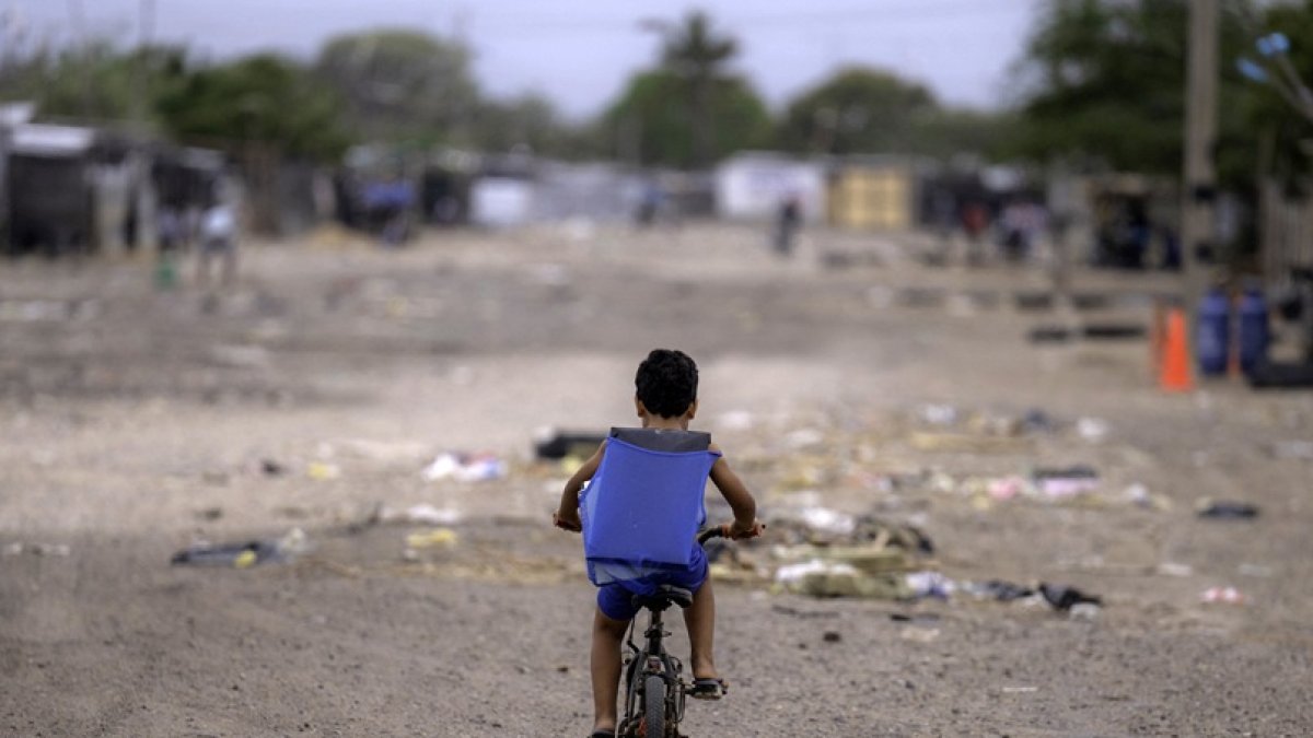 Un niño migrante venezolano monta su bicicleta en el campamento de migrantes La Pista en Maicao, departamento de La Guajira, Colombia.