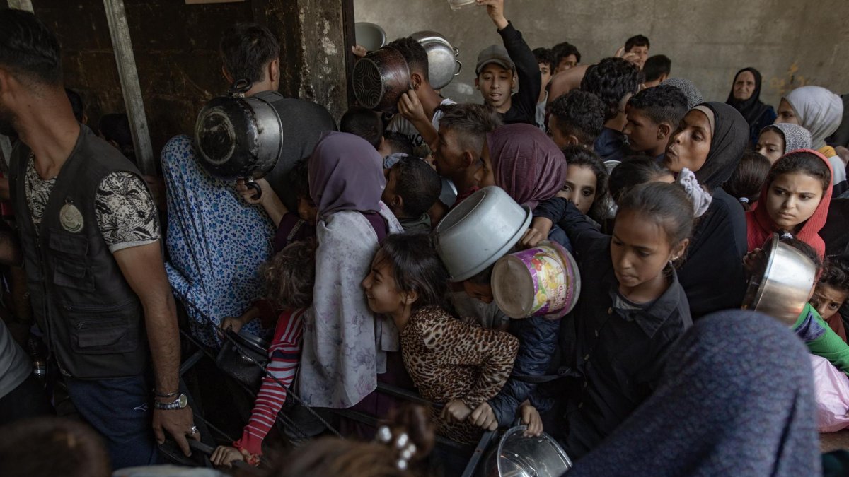 Cientos de palestinos se amontonan frente al Comedor Social Sokar en la Ciudad de Gaza para conseguir raciones de comida.
