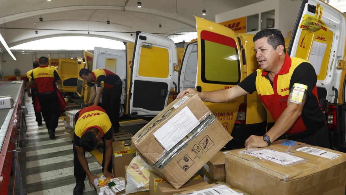 Personas trabajan en una empresa que ofrece el servicio de entrega de paquetes en casa.