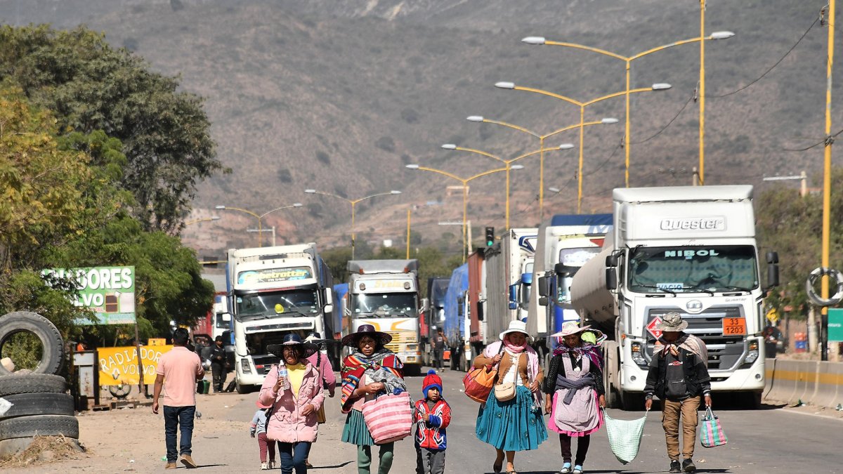 Personas caminan por una carretera tras un bloqueo realizado por seguidores del exmandatario Evo Morales, en Sipe Sipe en la región de Cochabamba (Bolivia).