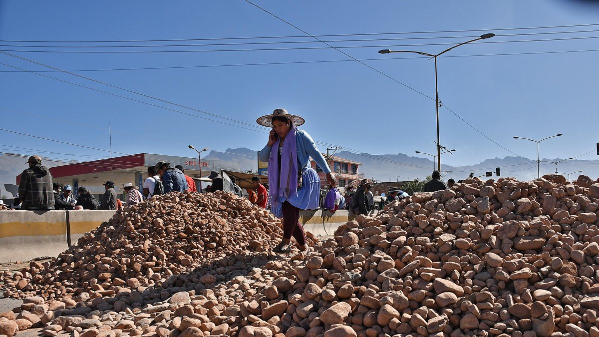 Una mujer captada este 2 de junio al pasar sobre un montículo de piedras, que bloquean una carretera a la altura de la localidad de Sipe Sipe, en la región de Cochabamba (Bolivia).