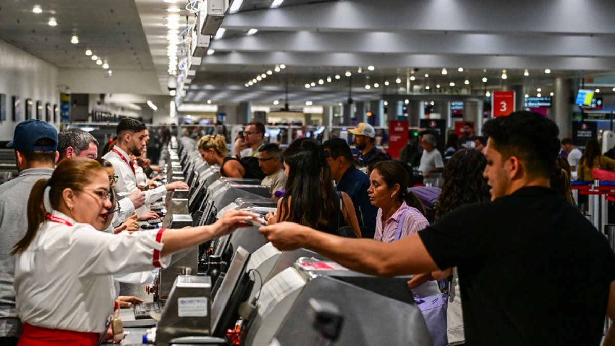 Los viajeros entregan documentos al personal de la aerolínea en el Aeropuerto Internacional de Miami durante el 24 de mayo de 2025 en Miami, Florida.