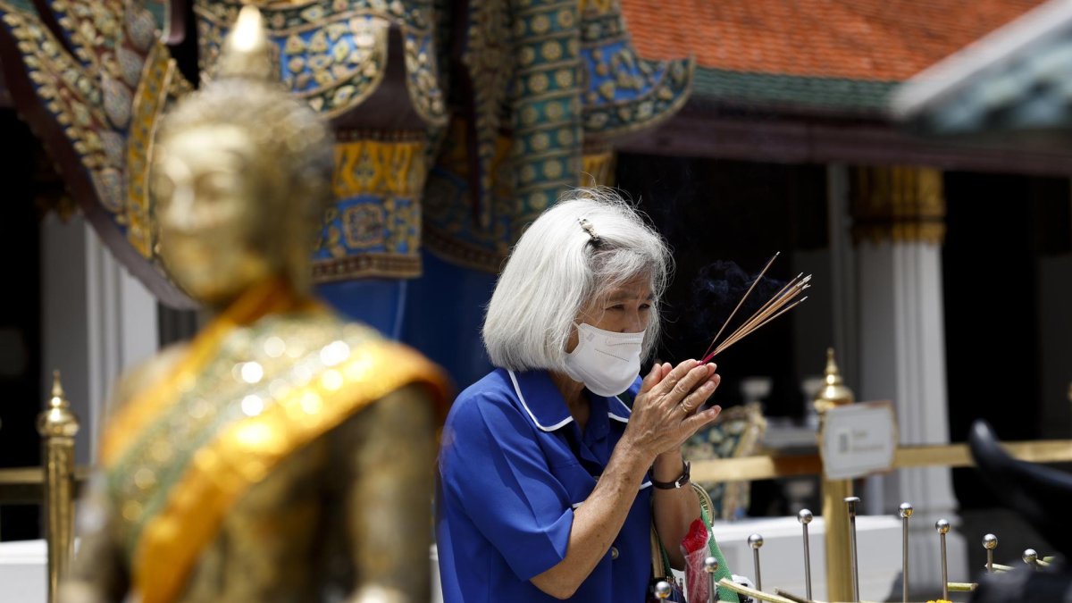 Una mujer usando mascarilla durante una visita a un sitio budista en Bangkok, Tailandia.