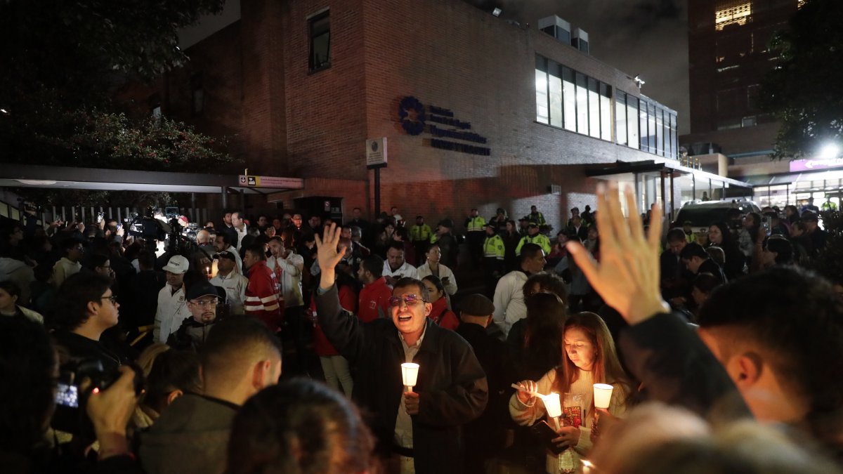 Personas encienden velas a las afueras de la Fundación Santa Fe donde fue trasladado el senador colombiano Miguel Uribe Turbay este sábado.