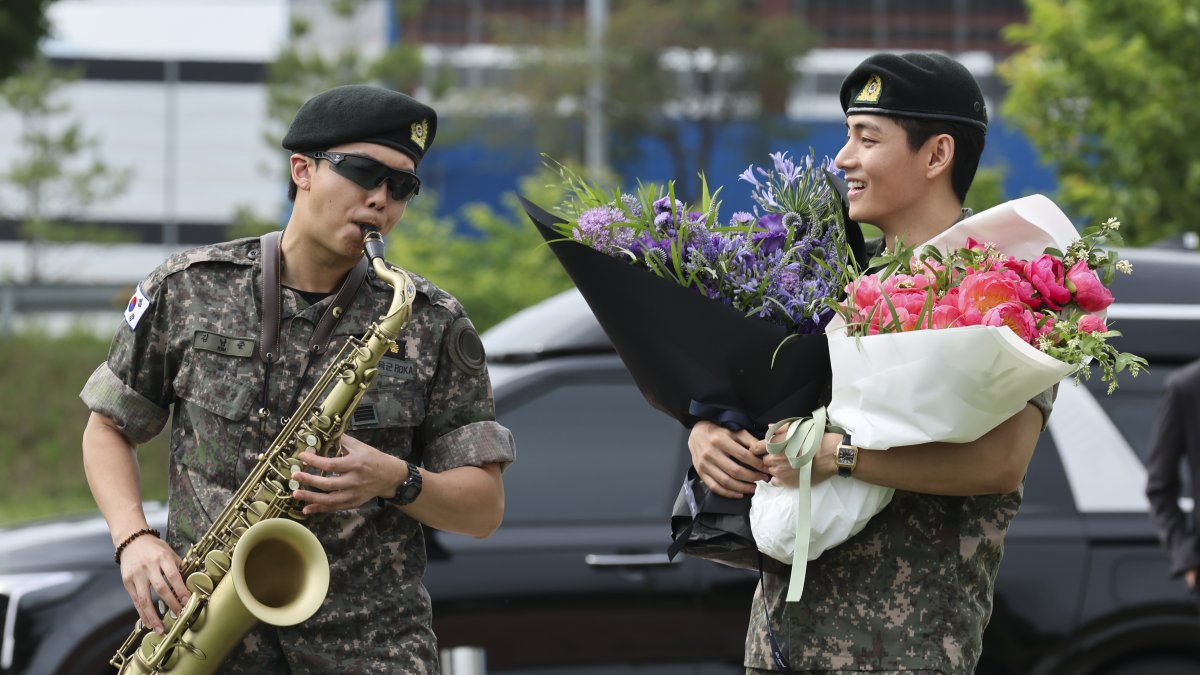 RM toca el saxofón junto a su compañero de banda V, mientras sus fans disfrutan de su salida, luego de completar 18 meses de servicio militar obligatorio.