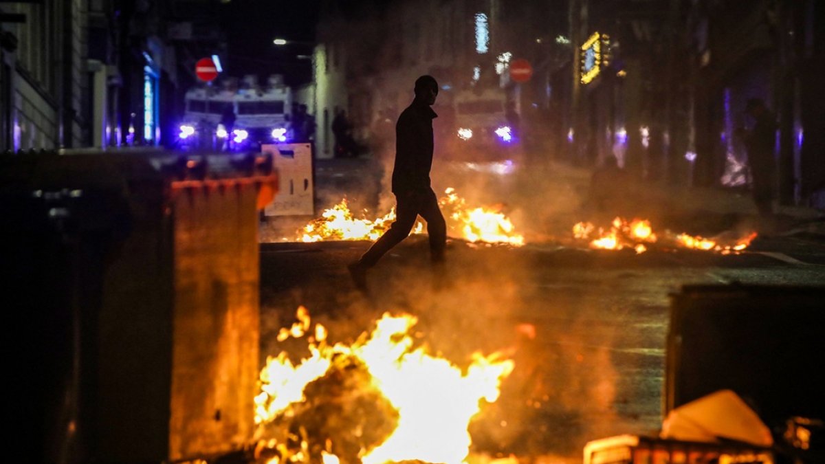 Un manifestante camina junto a un incendio en la calle durante una manifestación contra la inmigración en Ballymena, Irlanda del Norte, el 10 de junio de 2025.