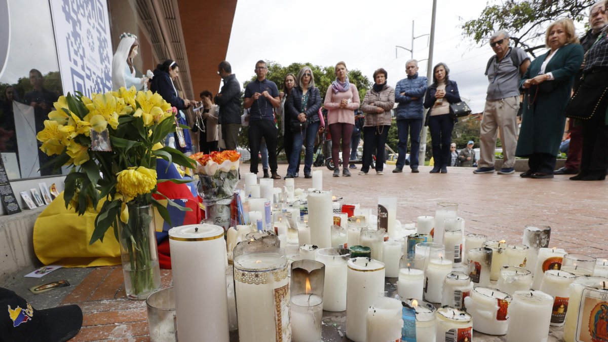 Personas observan un altar en honor al senador y precandidato presidencial Miguel Uribe Turbay, este miércoles en una de las entradas de la Fundación Santa Fe de Bogotá (Colombia).