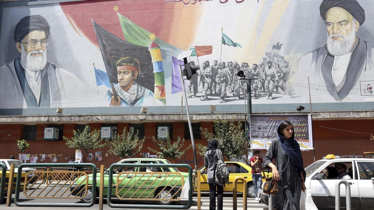 Ciudadanos iraníes caminan junto a un cartel que representa al líder supremo de Irán, ayatolá Ali Jamenei,  en una calle de Teherán, Irán.