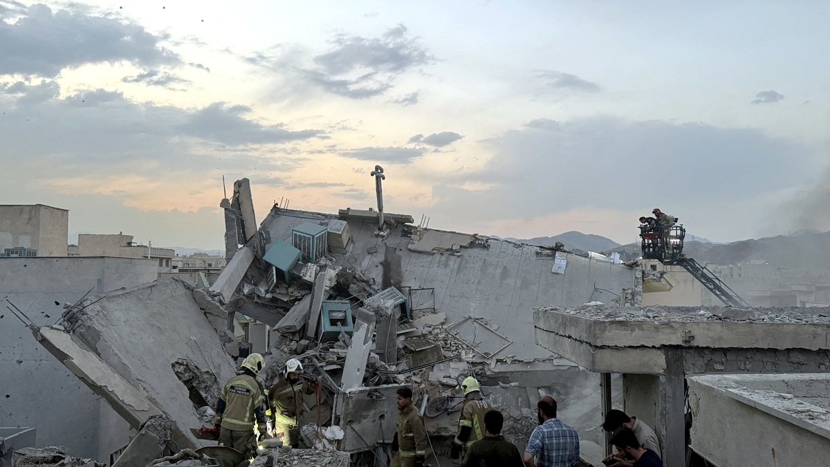 Personas y personal de emergencia se reúnen encima de un edificio que fue alcanzado por un ataque israelí en Teherán el 13 de junio de 2025.