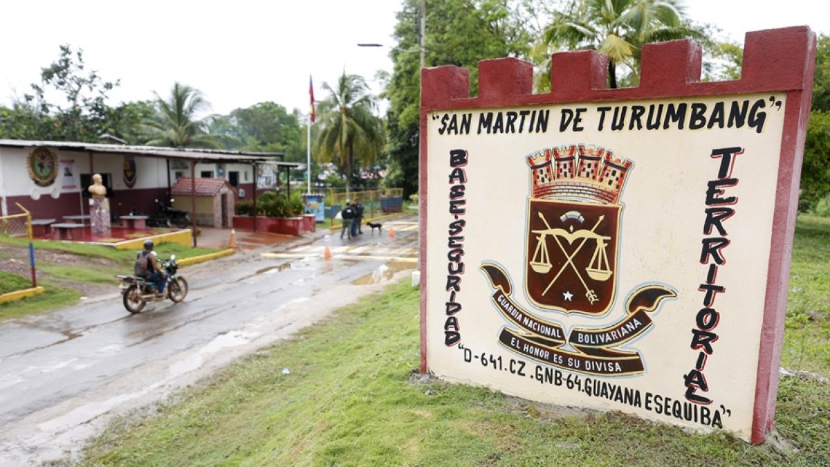 Una motocicleta pasa junto a un cartel de la Guardia Nacional Bolivariana a la entrada del pueblo de San Martín de Turumbang, estado Bolívar, Venezuela.