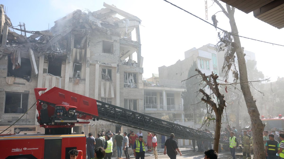 Bomberos, rescatistas y personal de seguridad trabajan alrededor de un edificio que fue alcanzado por ataques aéreos israelíes en el centro de Teherán, Irán, el 13 de junio de 2025.