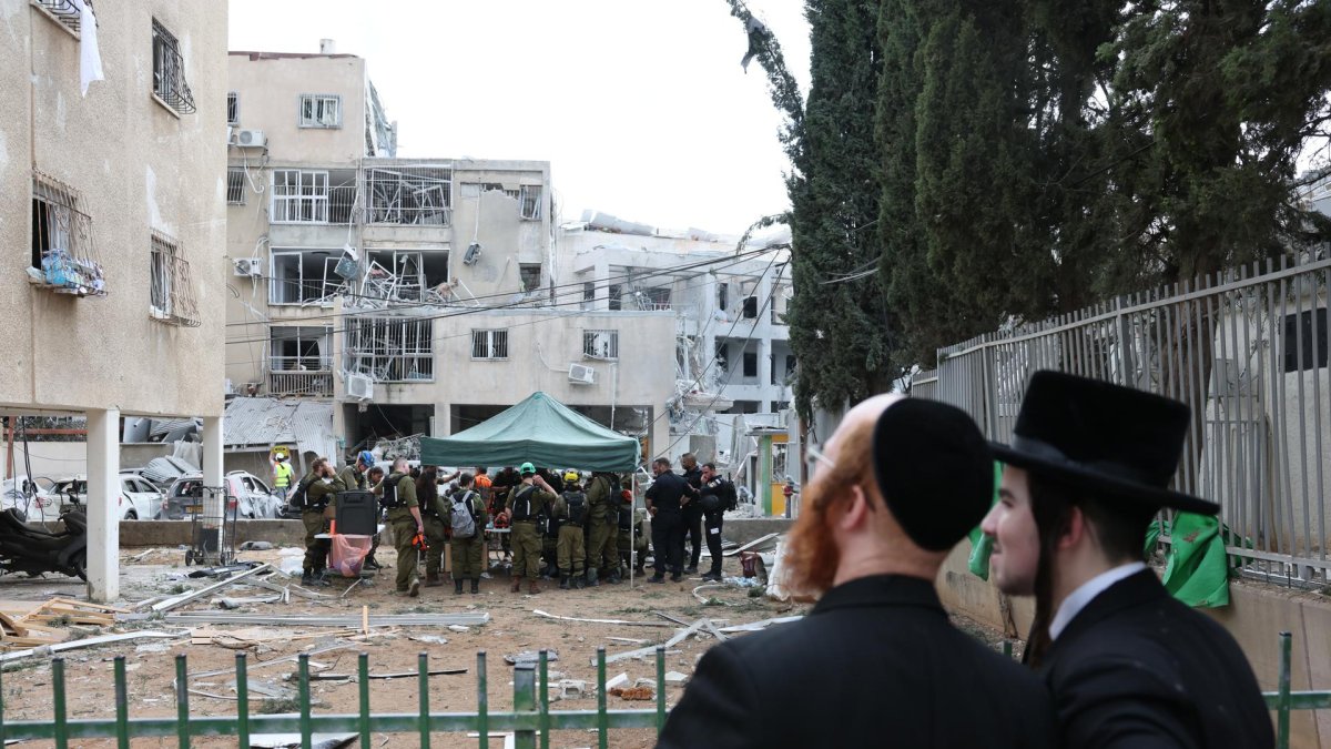 Dos hombres judíos ultraortodoxos cerca de una escuela de niñas judías dañada después de que misiles balísticos iraníes impactaran Bnei Brak, en el centro de Israel, el 16 de junio de 2025.